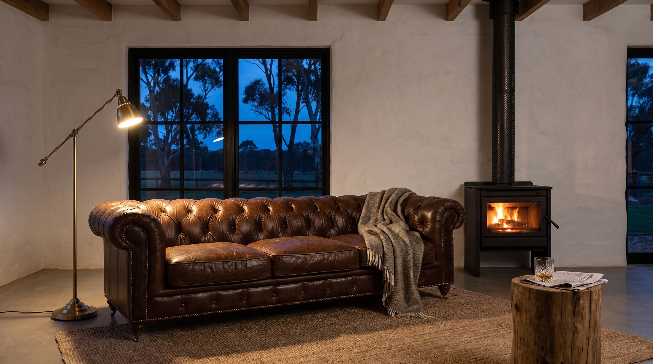 The farmhouse at dusk, with a lamp lit beside the leather lounge